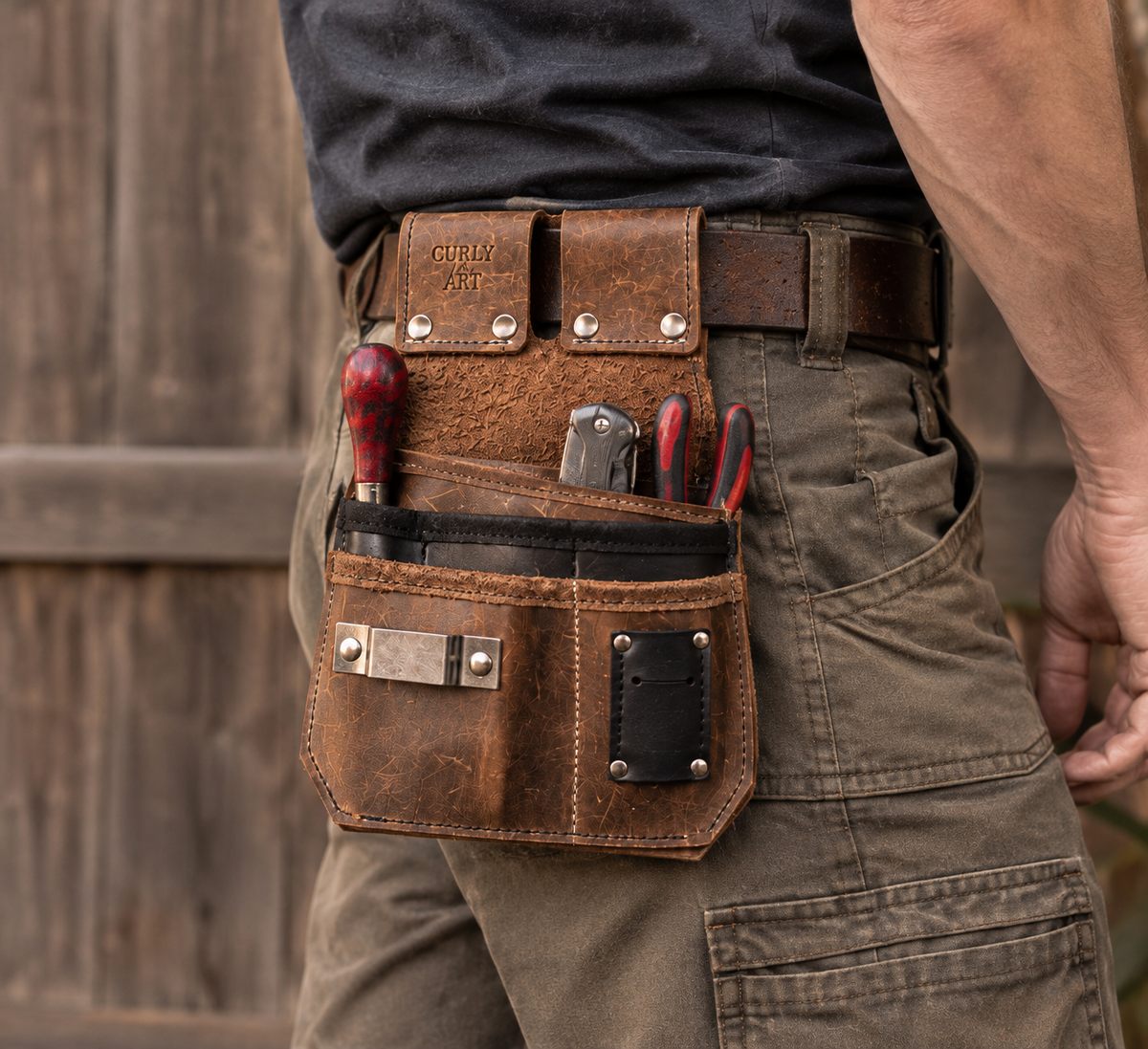 Person trägt eine braune Allround-Werkzeugtasche aus Leder mit Schraubendrehern und Zange am Gürtel