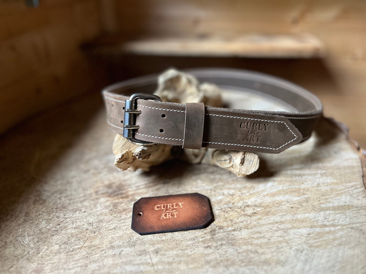 Brauner Ledergürtel mit Doppeldornschnalle, hellen Nähten und geprägtem Curly Leather Art Logo