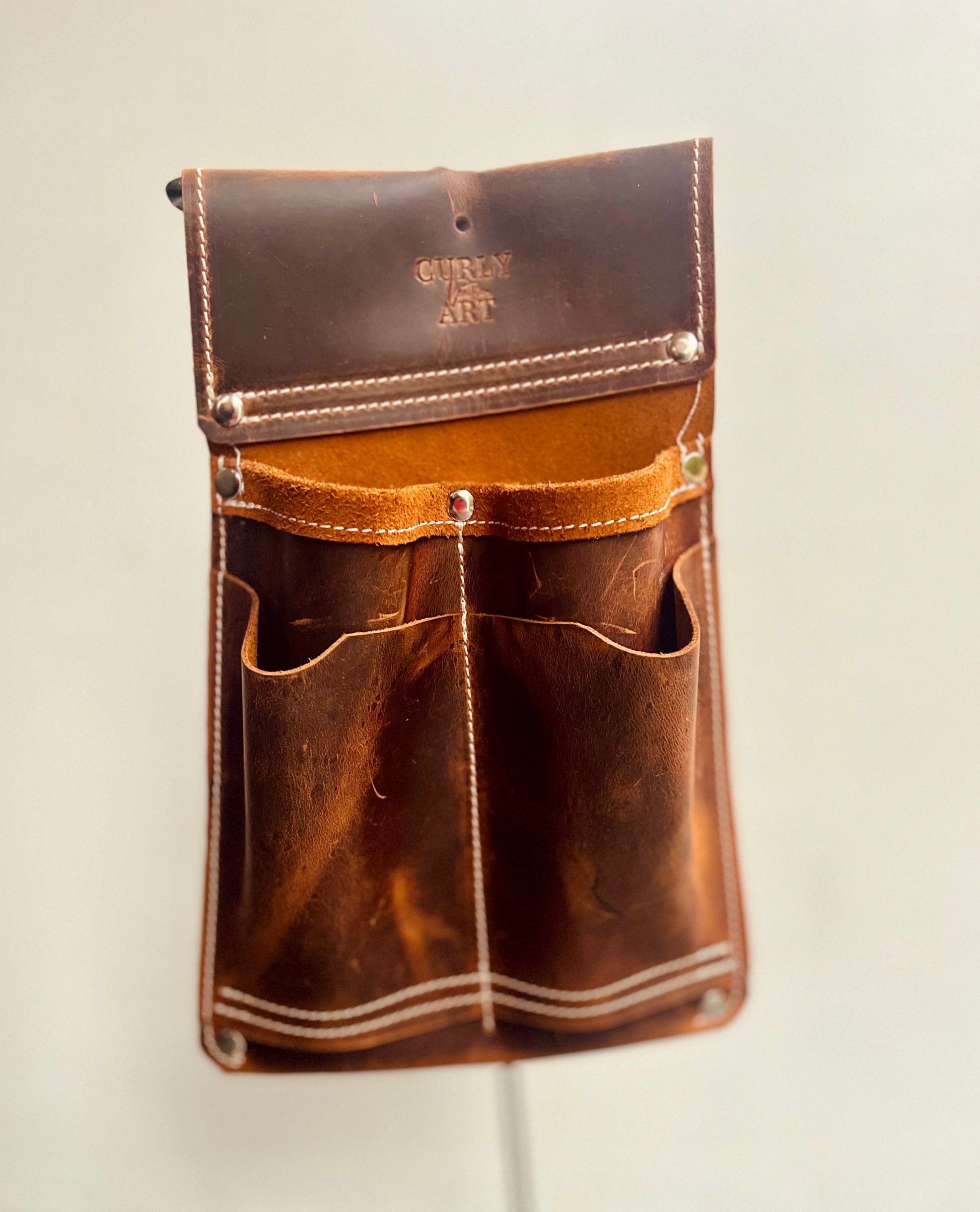 Braune 4-Fächer-Werkzeugtasche aus Leder ohne Hammerschlaufe mit hellen Nähten vor hellem Hintergrund