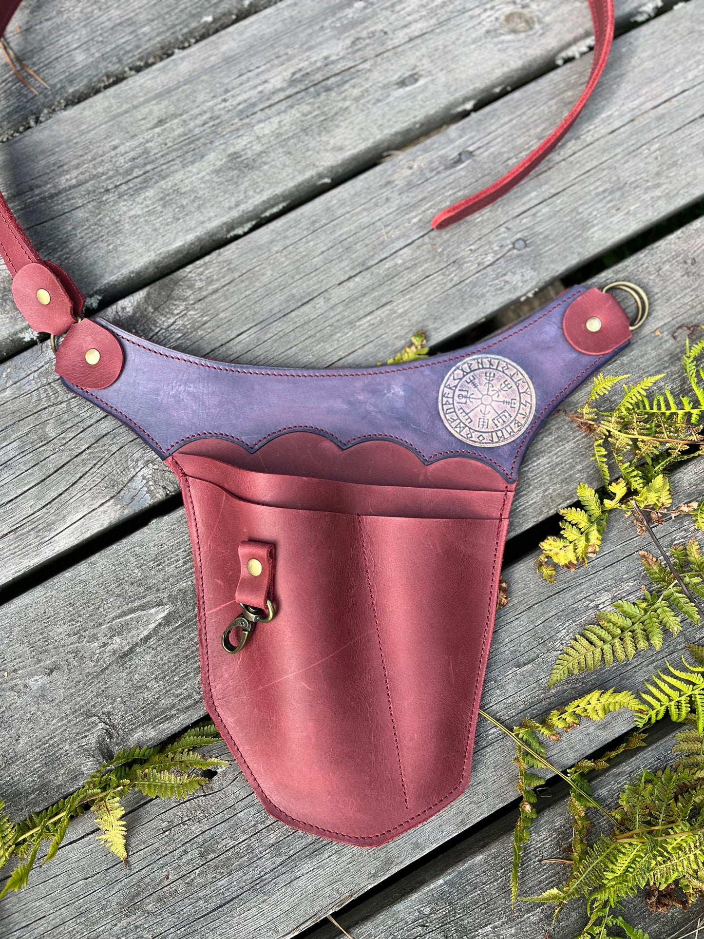 Weinroter Gartenwerkzeuggürtel aus Leder mit violettem Vegvísir-Kranz auf Holz