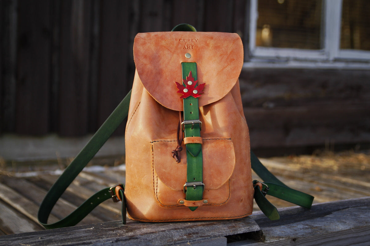 Heller Lederrucksack mit grünen Riemen, rotem Ahornblatt 